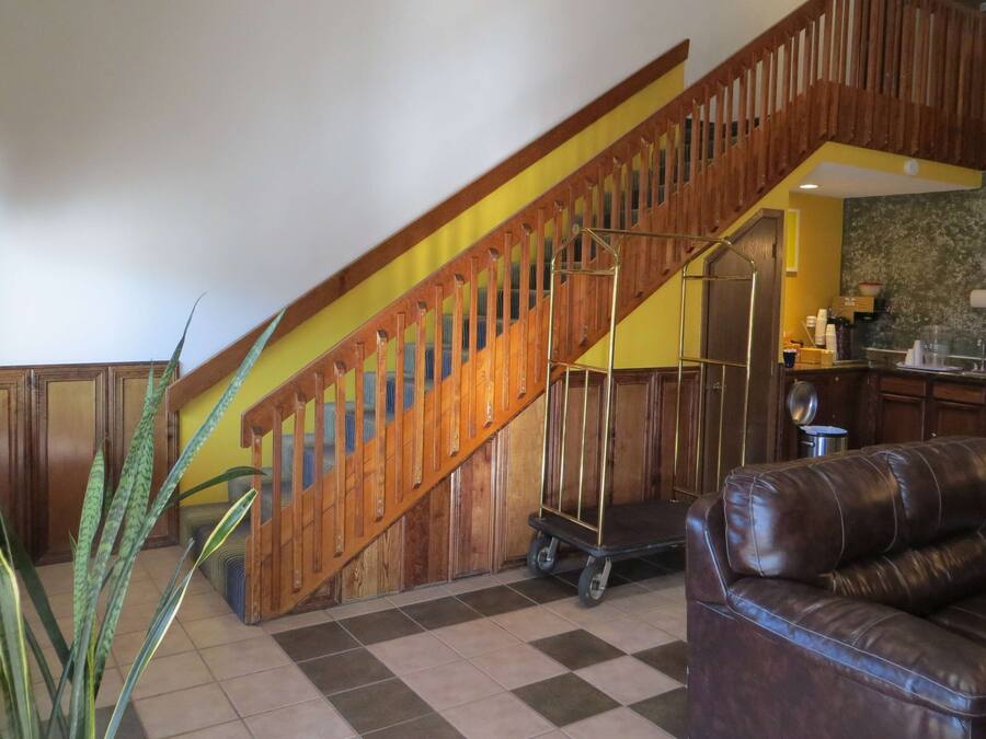 A staircase with wooden railings, a leather sofa, and a kitchen area with cabinets and a countertop.