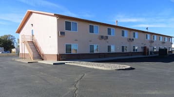 A two-story motel with a central staircase, multiple windows, and a parking lot.