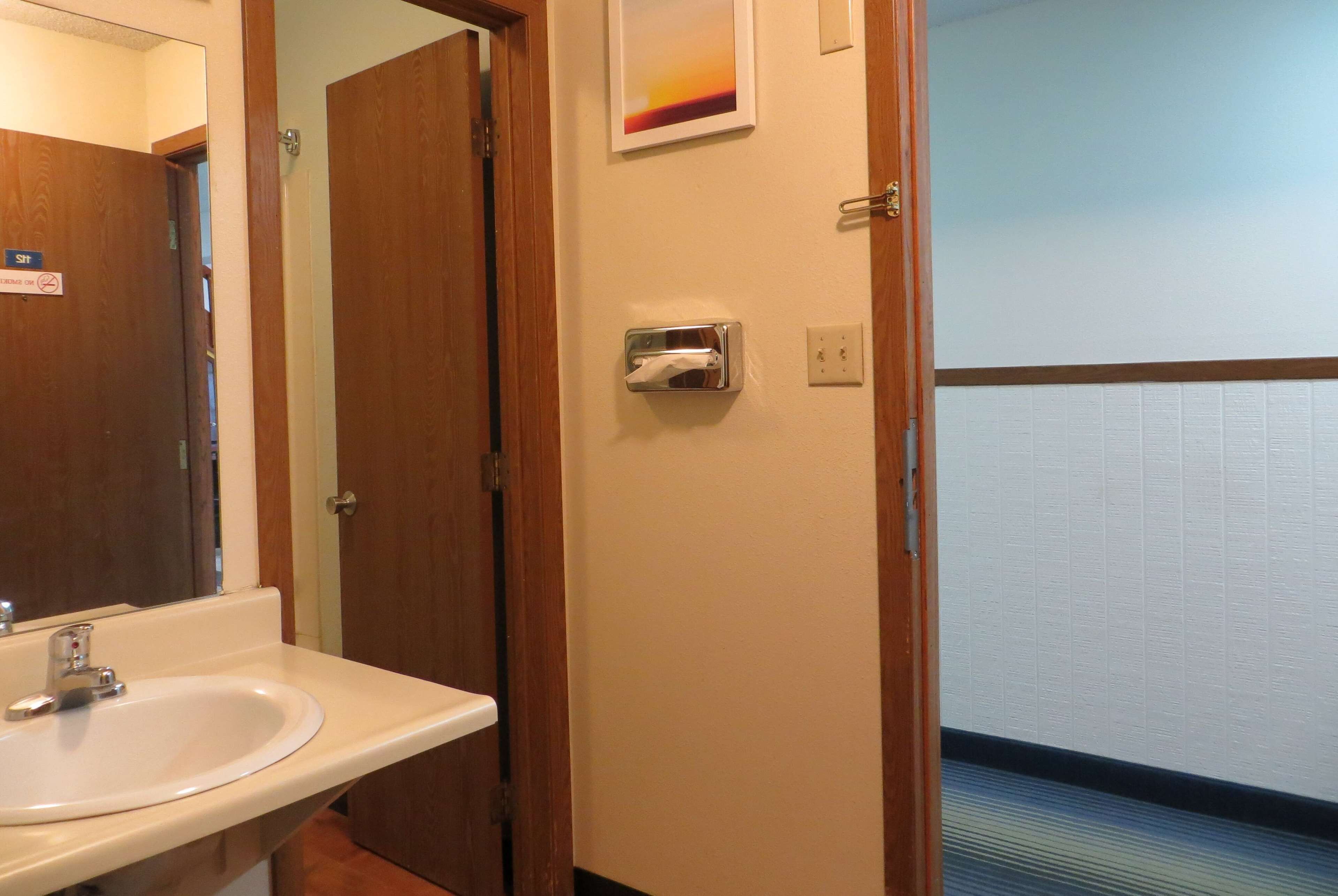 A bathroom with a sink, a hand dryer, and a towel dispenser.