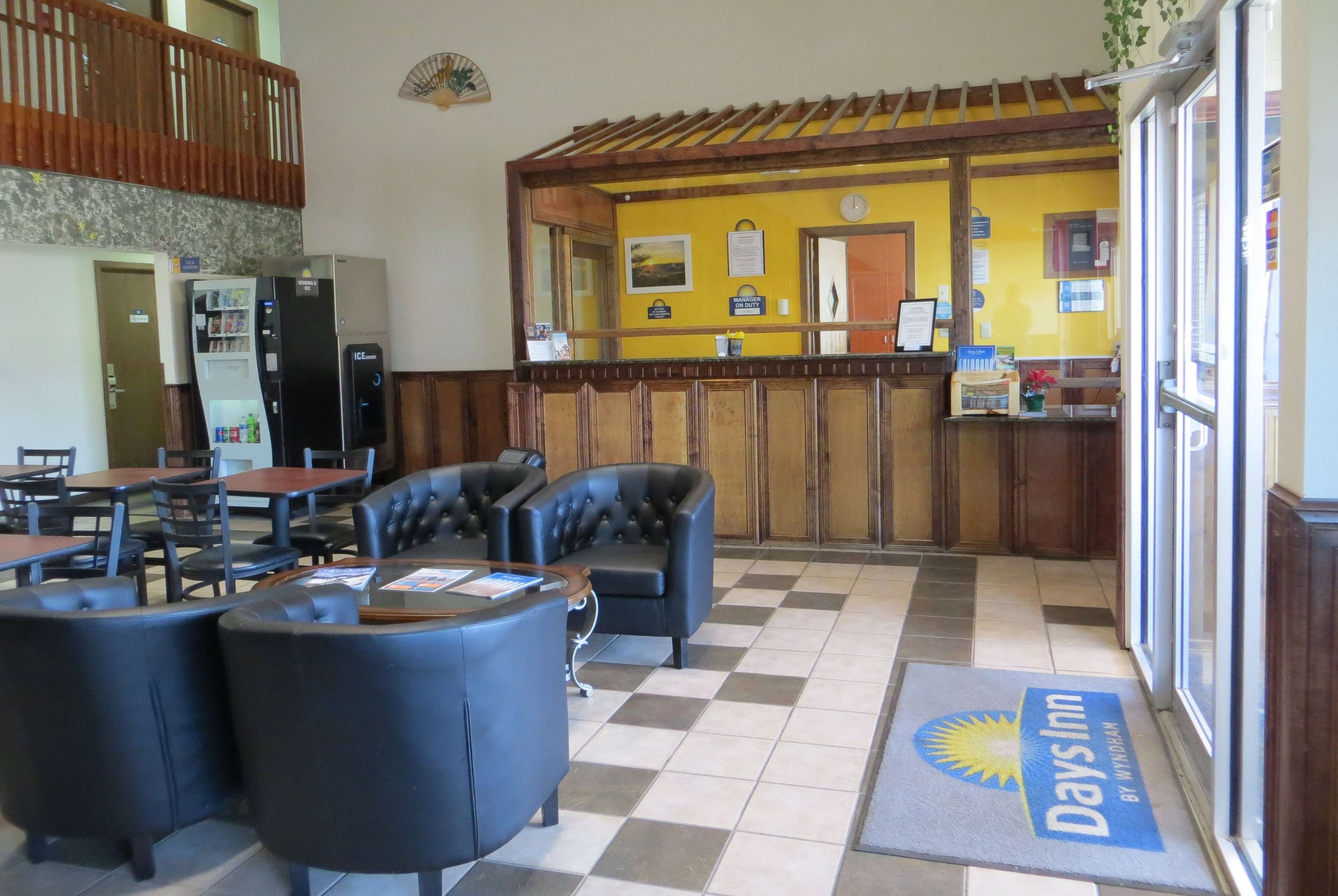 A hotel lobby with a check-in counter, seating area, and a refrigerator.