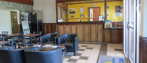 A hotel lobby with a check-in counter, seating area, and a refrigerator.