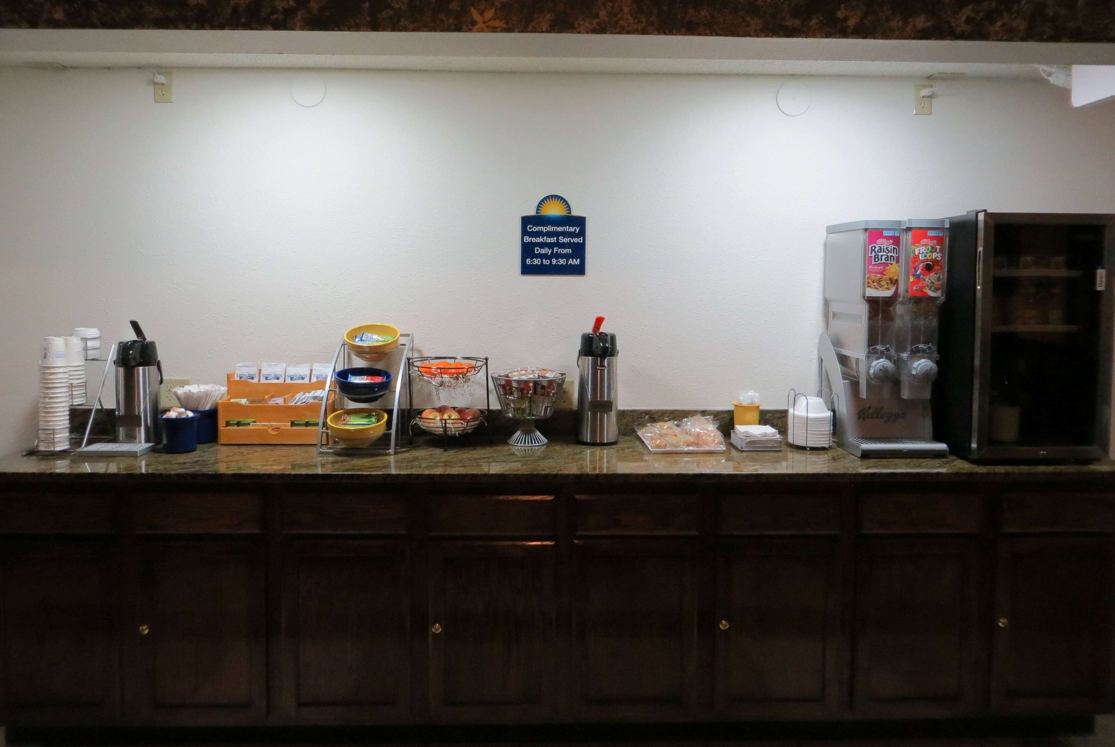 Un buffet pour le petit-déjeuner proposant divers aliments, ainsi qu’un panneau indiquant que le petit-déjeuner est offert.
