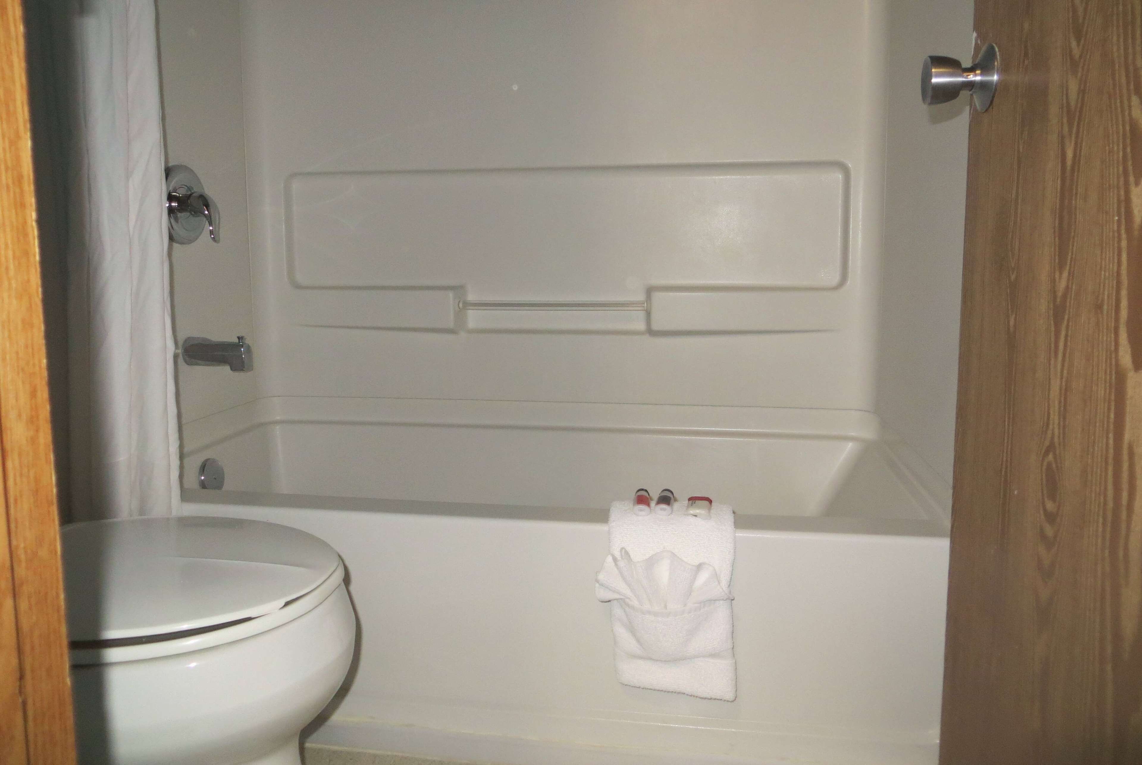 Un baño con inodoro, bañera y toallero con una toalla doblada.