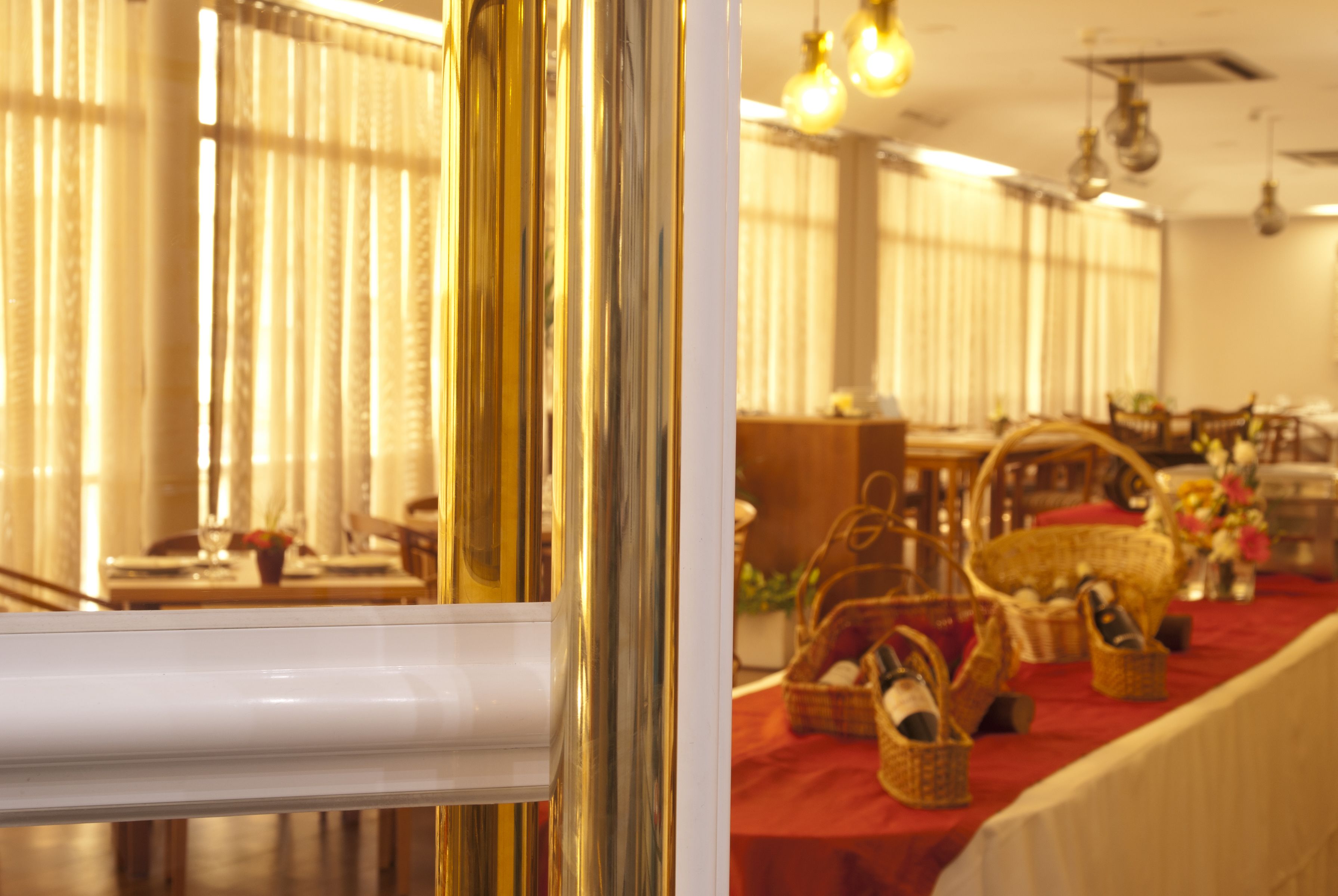 A dining area with tables set for a meal, featuring wicker baskets and a red tablecloth.