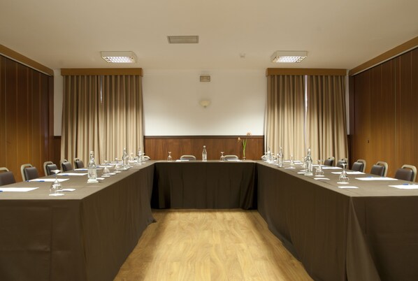 Un salón de conferencias con una mesa larga, sillas y piso de madera.