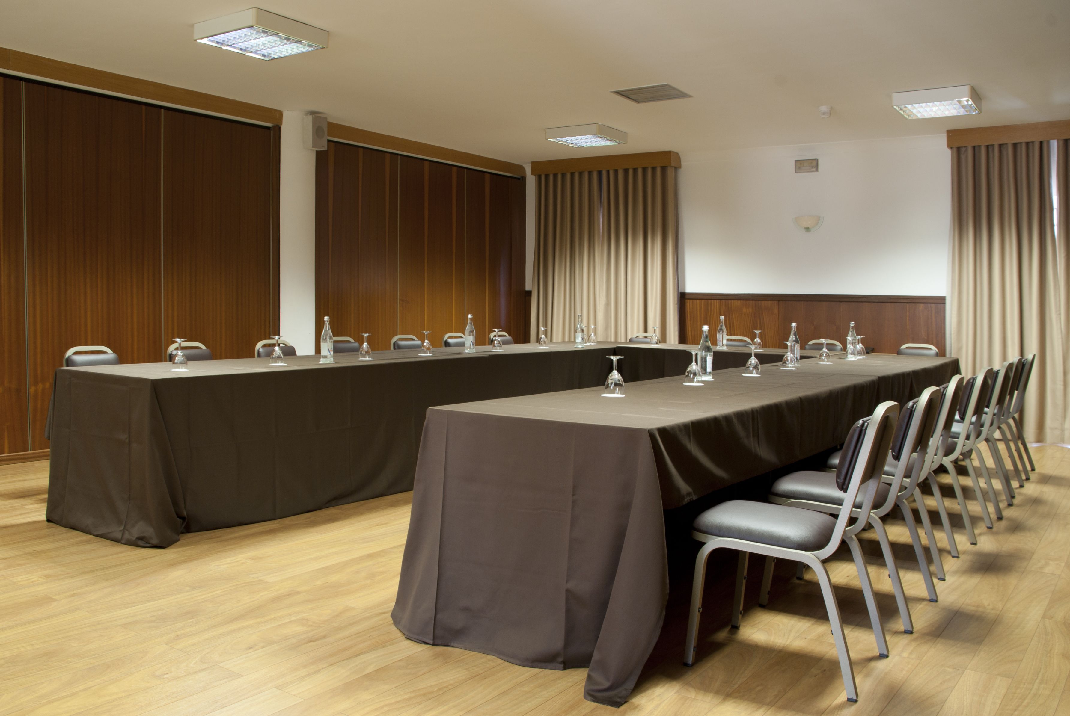 A conference room with a long table, chairs, and a projector screen.