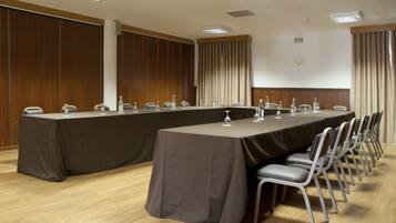 A conference room with a long table, chairs, and a projector screen.