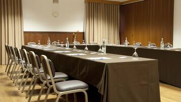 A conference room with a long table, chairs, and a wooden panel wall.