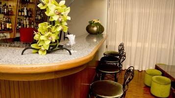 A bar area with a curved counter, a vase with flowers, and a seating arrangement with chairs and ottomans.