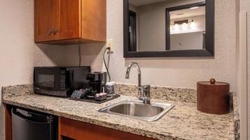 Una cocina con encimera de granito, pileta de acero inoxidable y armarios de madera.
