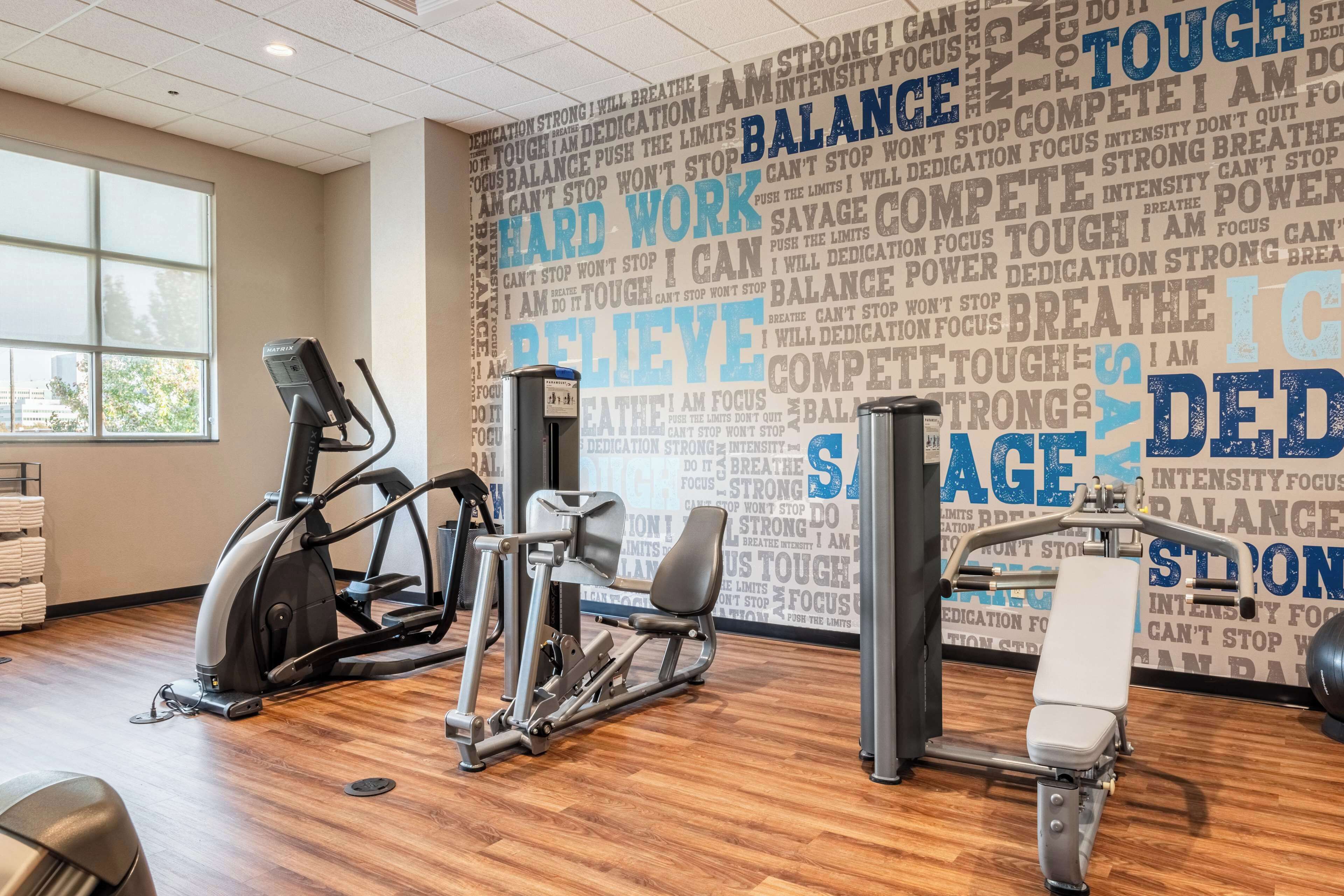 Een sportschool met trainingsapparatuur en motiverende teksten op de muur.