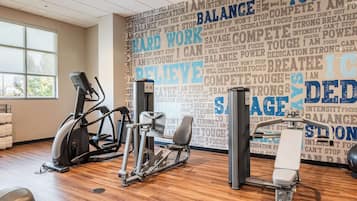 Een sportschool met trainingsapparatuur en motiverende teksten op de muur.