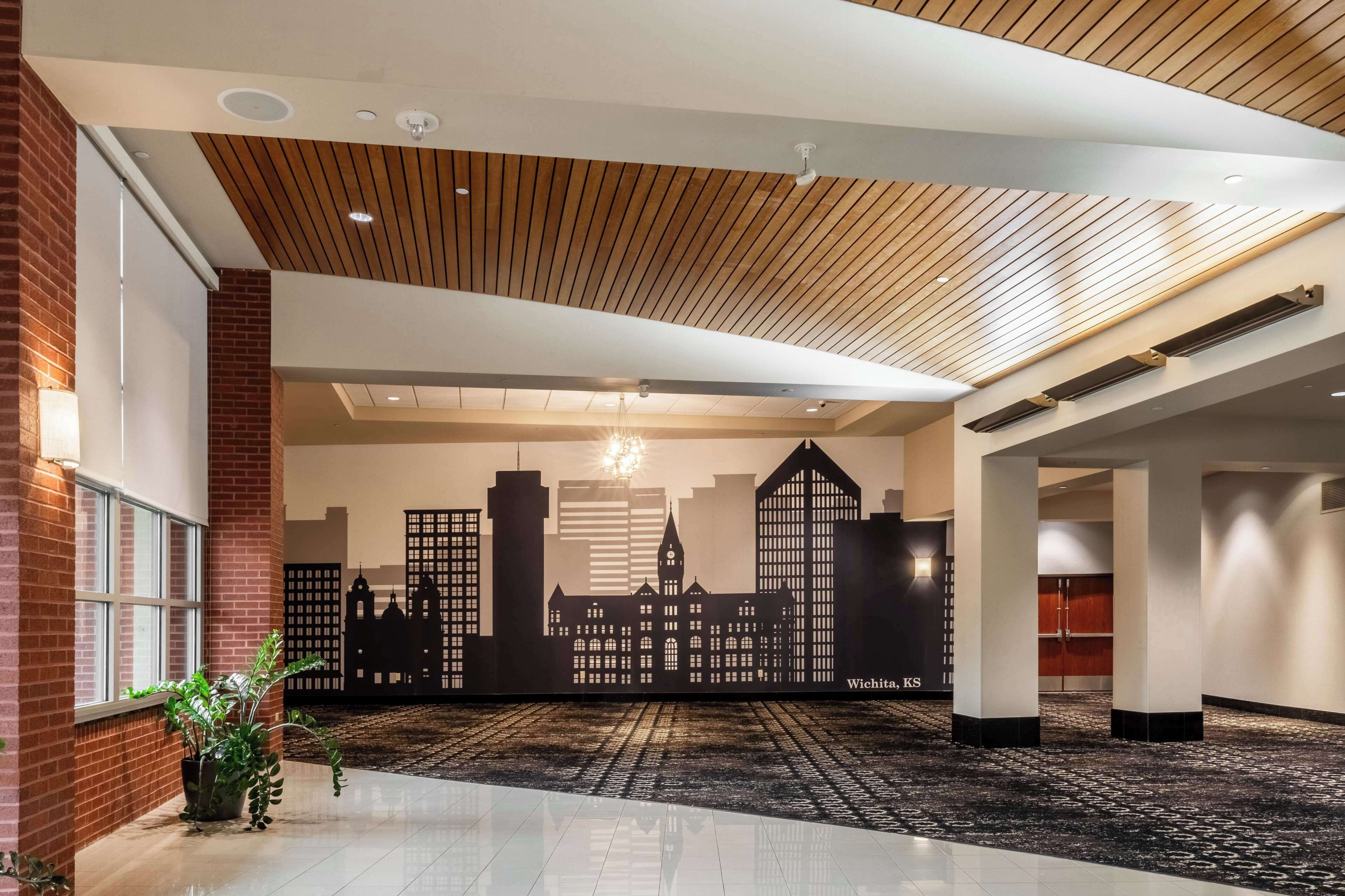 A hotel lobby with a cityscape mural, wooden ceiling, and a polished floor.