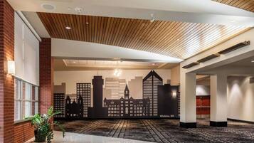 A hotel lobby with a cityscape mural, wooden ceiling, and a polished floor.
