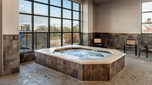 A spa area with a hot tub, large windows, and stone walls. - Drury Plaza Hotel Broadview - Wichita (Wichita)
