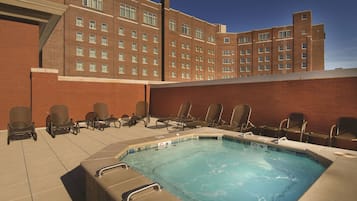 Relax by the pool surrounded by the hotel's brick facade and multiple windows.