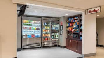 Interior de una tienda de comestibles con mostradores refrigerados para bebidas y estantes con productos de snack.