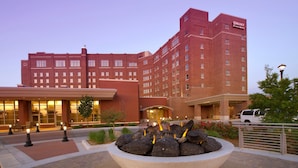 A hotel with a large stone fountain in the courtyard, a brick building facade, and a well-lit entrance. - Drury Plaza Hotel Broadview - Wichita (Wichita)