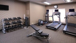 A gym with treadmills, a bench, dumbbells, and a wall-mounted TV. - Sonesta ES Suites Dallas Medical Market Center (Dallas)
