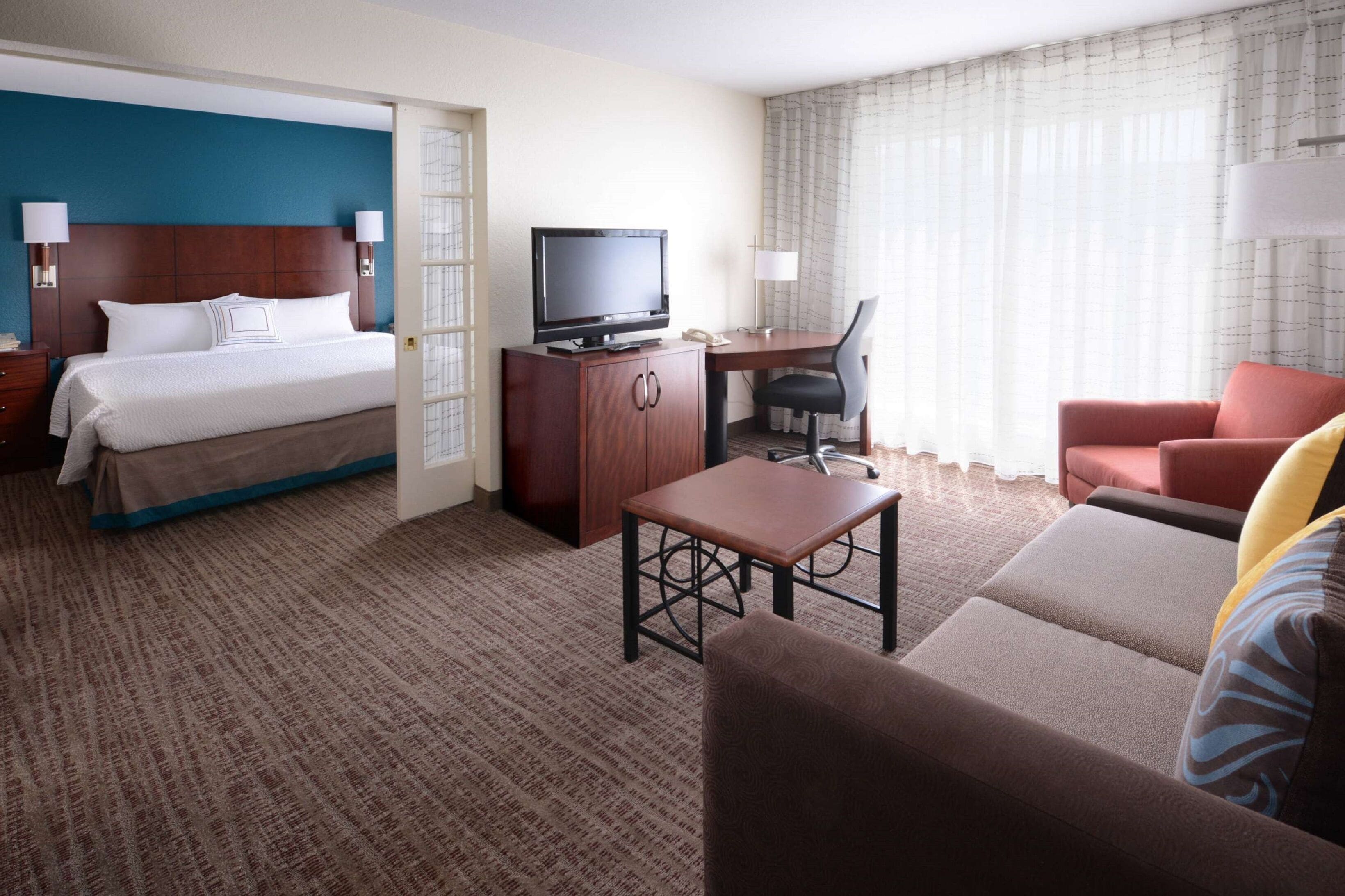 Een hotelkamer met een bed, een bureau met stoel, een televisie en een bank.