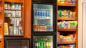 A snack and beverage refrigerator with shelves stocked with various snacks and drinks. - Sonesta ES Suites Dallas Medical Market Center (Dallas)