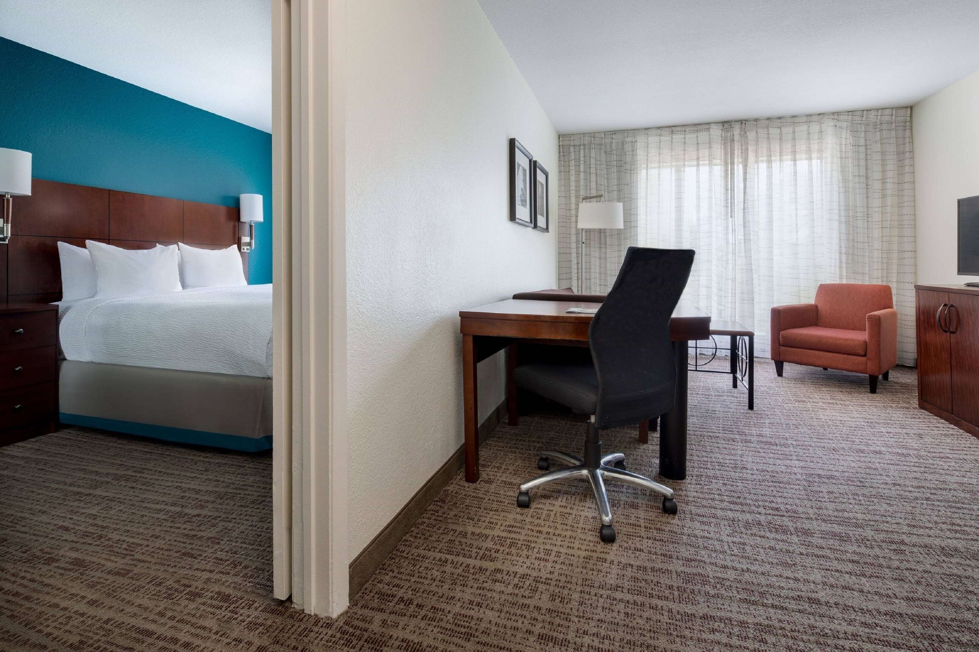Een hotelkamer met een bed, bureau, bureaustoel en een televisie.