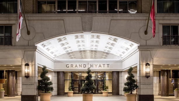 The Grand Hyatt hotel entrance with a prominent arched glass canopy, large potted trees, and flags. - Grand Hyatt Washington (Washington)