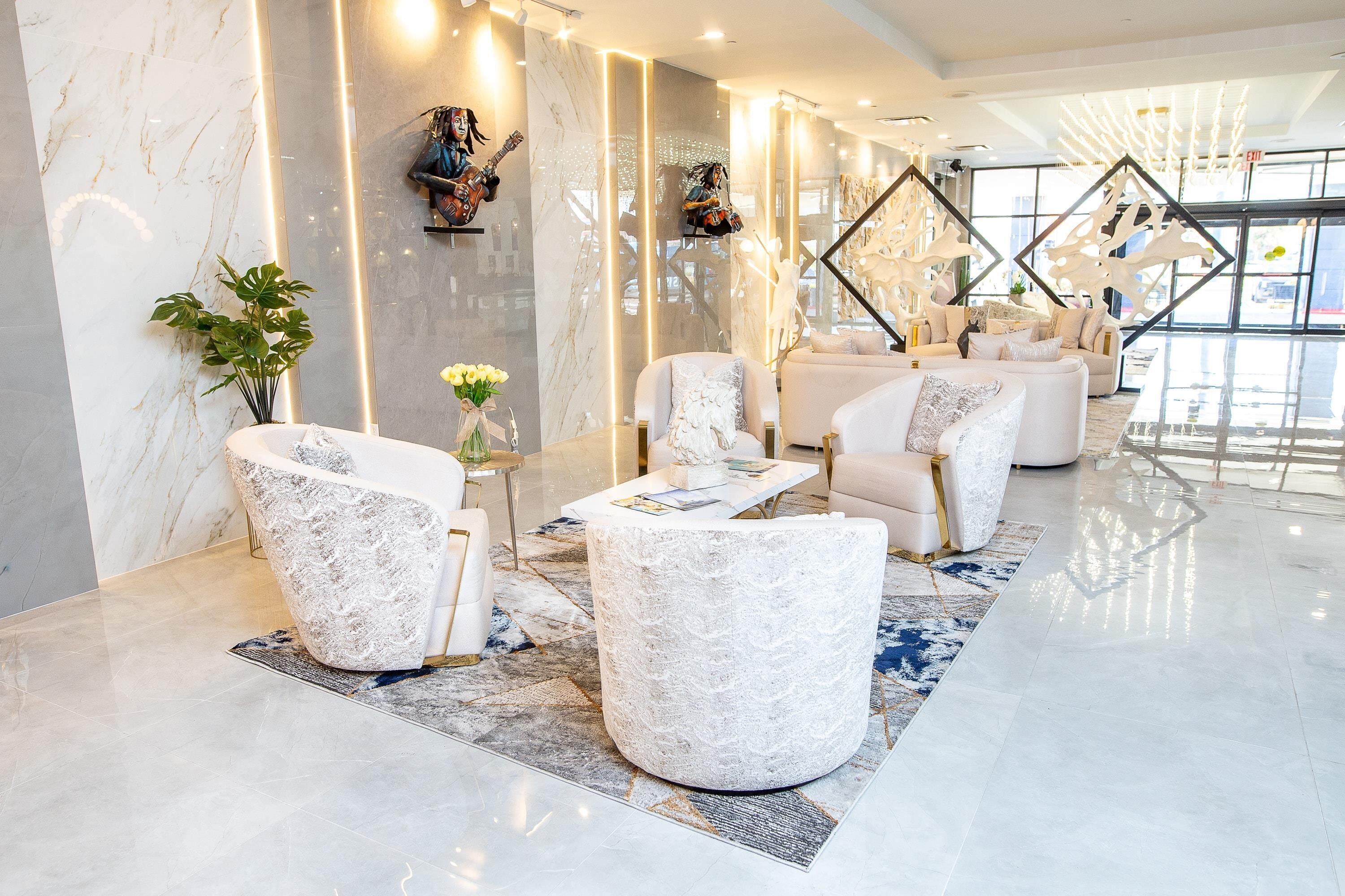 Un vestíbulo moderno con paredes de mármol, una zona de estar con sillones blancos y un amplio ventanal que proporciona luz natural.
