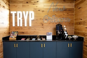 A wooden wall with 'TRYP New Orleans' signage, a coffee machine, and a counter with various items. - Wyndham New Orleans Airport & Conference Center (Kenner)