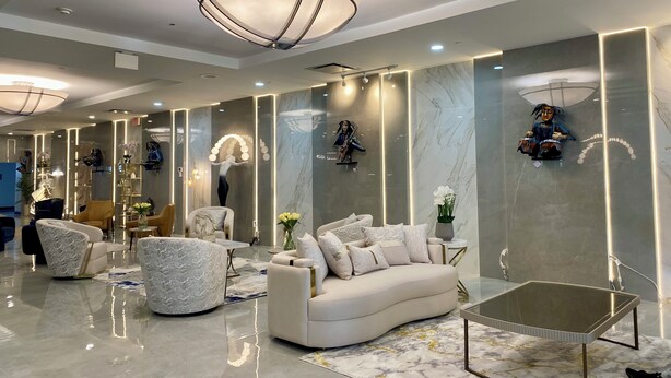A modern living room with a white sofa, a glass coffee table, and a marble floor.