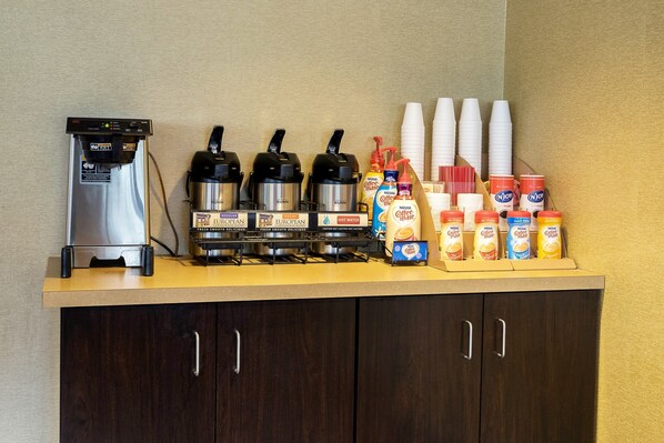 A coffee station with a coffee machine, three coffee makers, disposable cups, and coffee creamer dispensers. - Red Roof Inn Washington, PA (Washington)