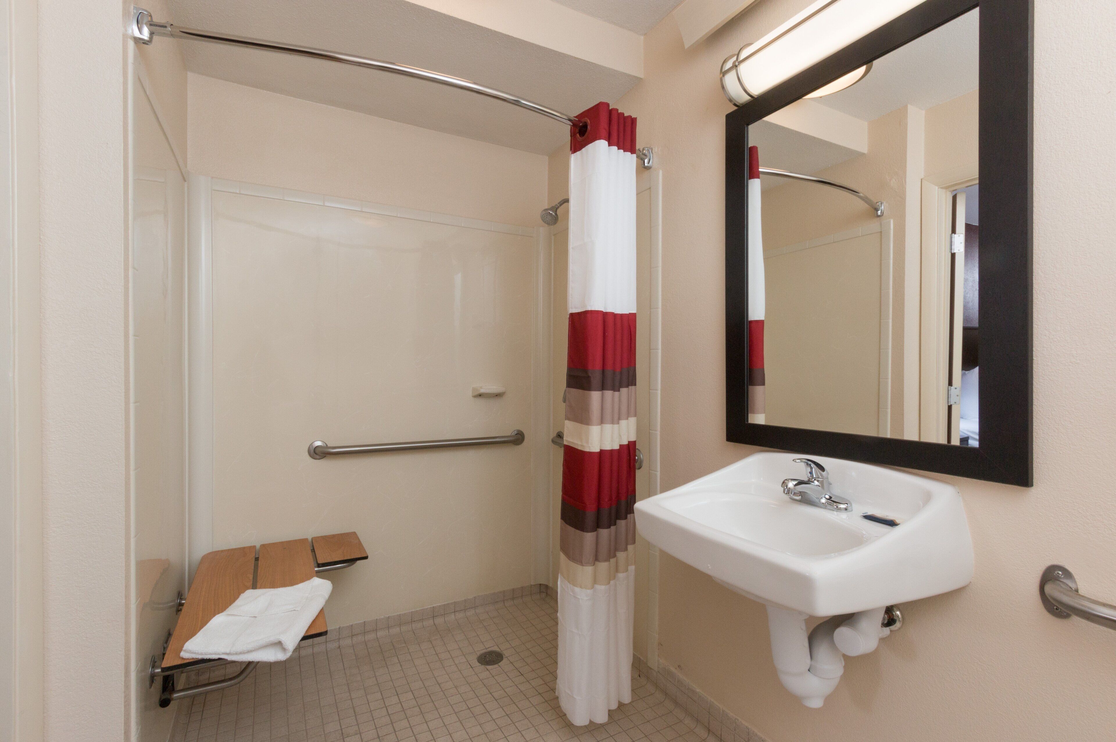 A bathroom with a shower, a sink, and a mirror.