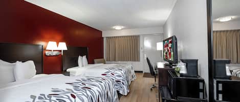 Une chambre d’hôtel avec un grand lit, un bureau avec un ordinateur, une télévision et une machine à café.