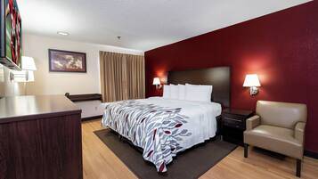 Habitación de hotel con una cama, mesitas de noche, un escritorio, una silla, una lámpara y un cuadro en la pared.
