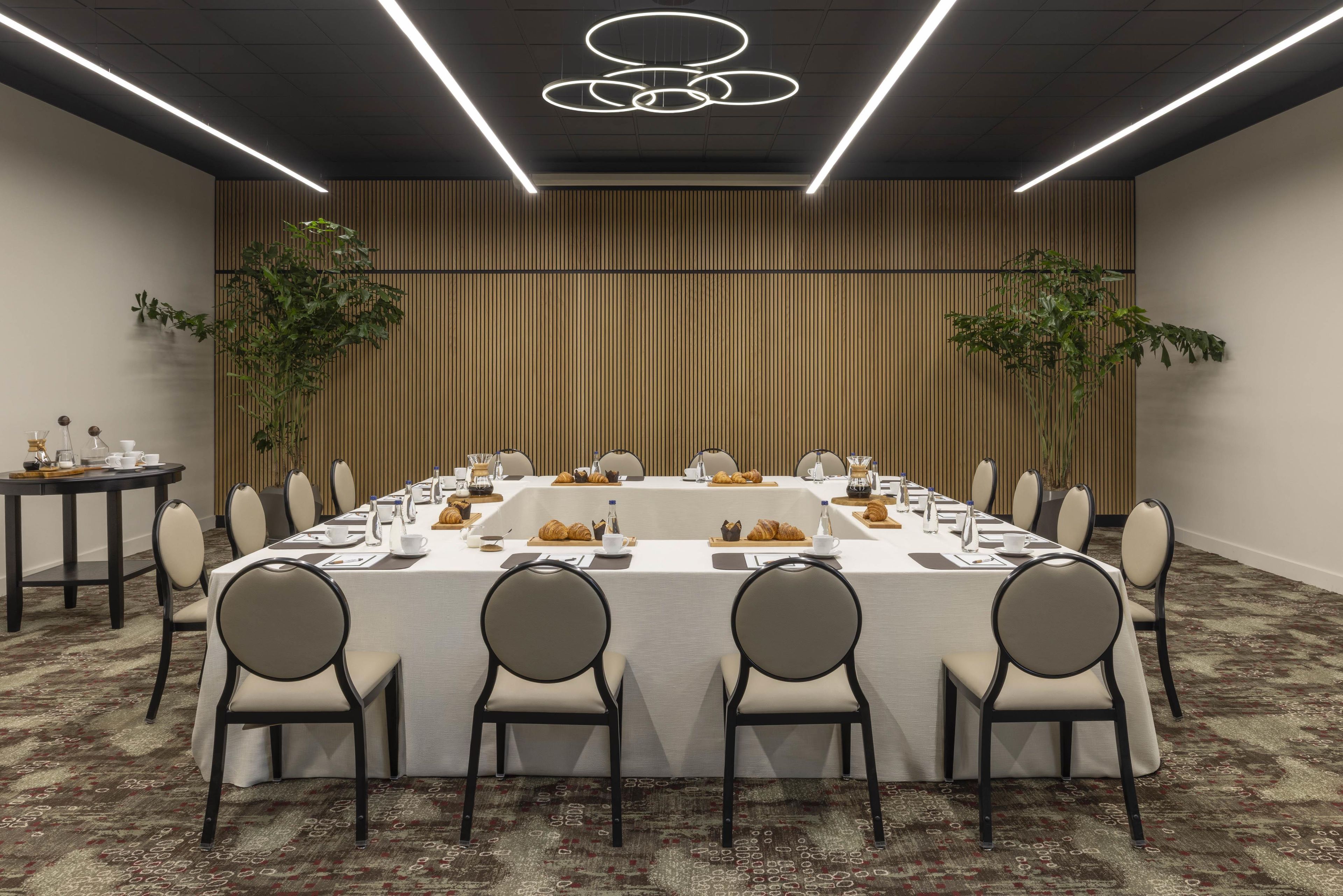 A conference room with a long table, chairs, and a modern ceiling light fixture.