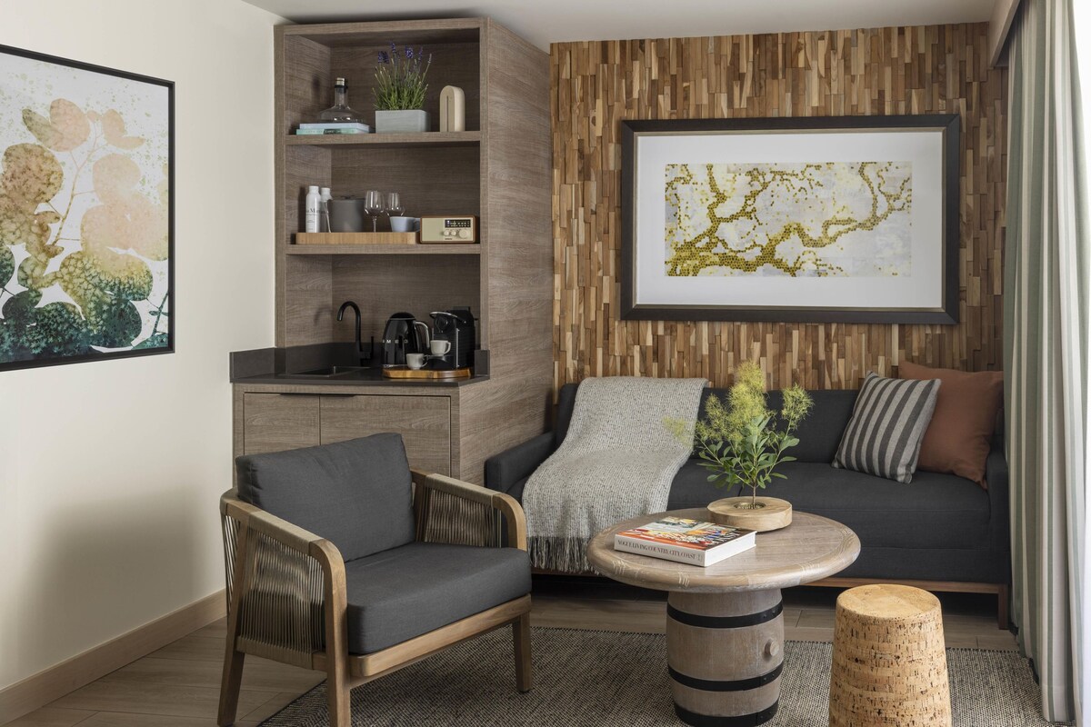 A modern living room with a sofa, armchair, coffee table, and a bookshelf.