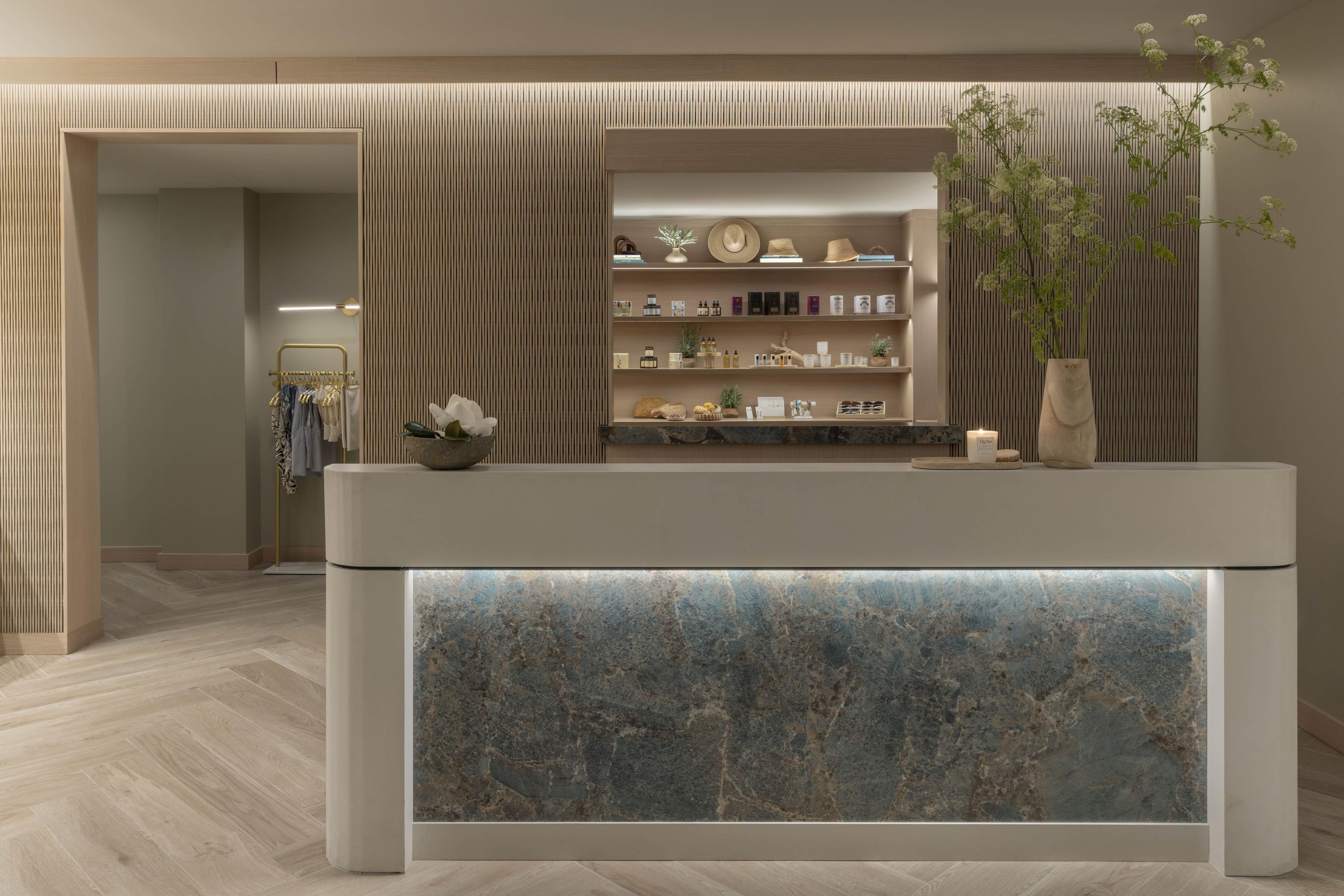 A reception area with a marble counter, a clothing rack, and a wall-mounted shelf with various items.