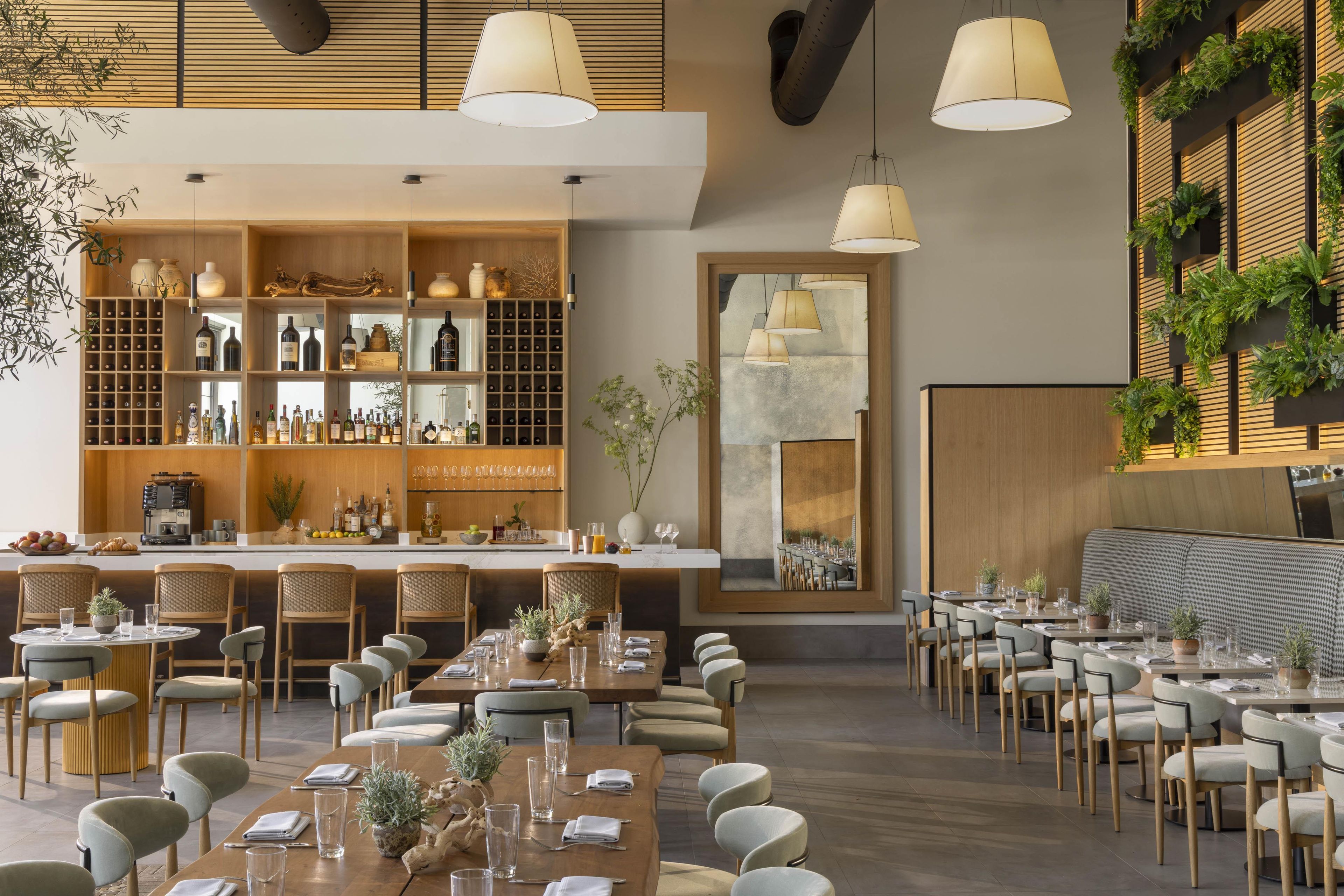 A modern restaurant with a bar area, multiple dining tables, and chairs.