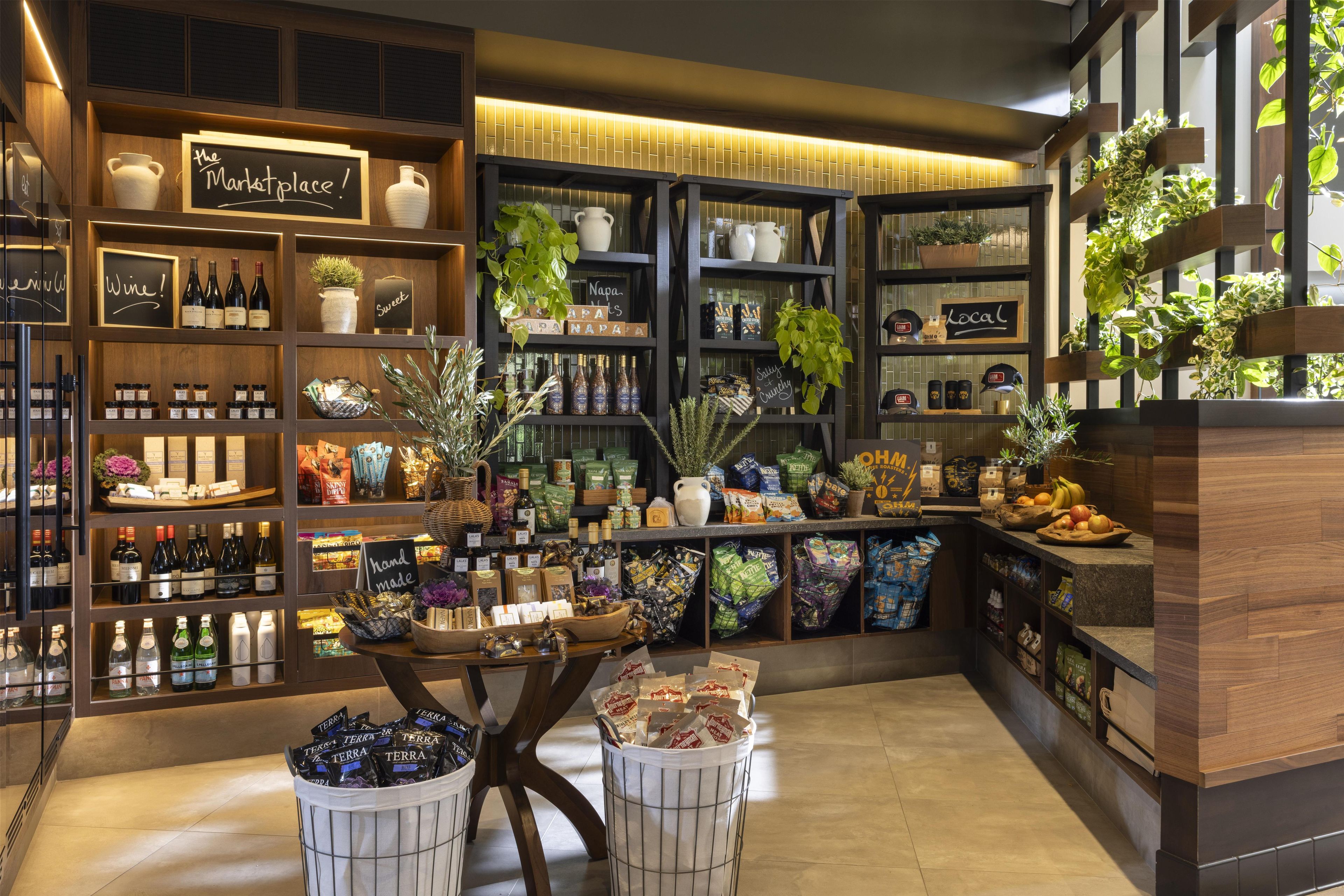 Un espacio comercial ordenado, con estantes repletos de diversos productos, como vino, bocadillos y alimentos envasados.