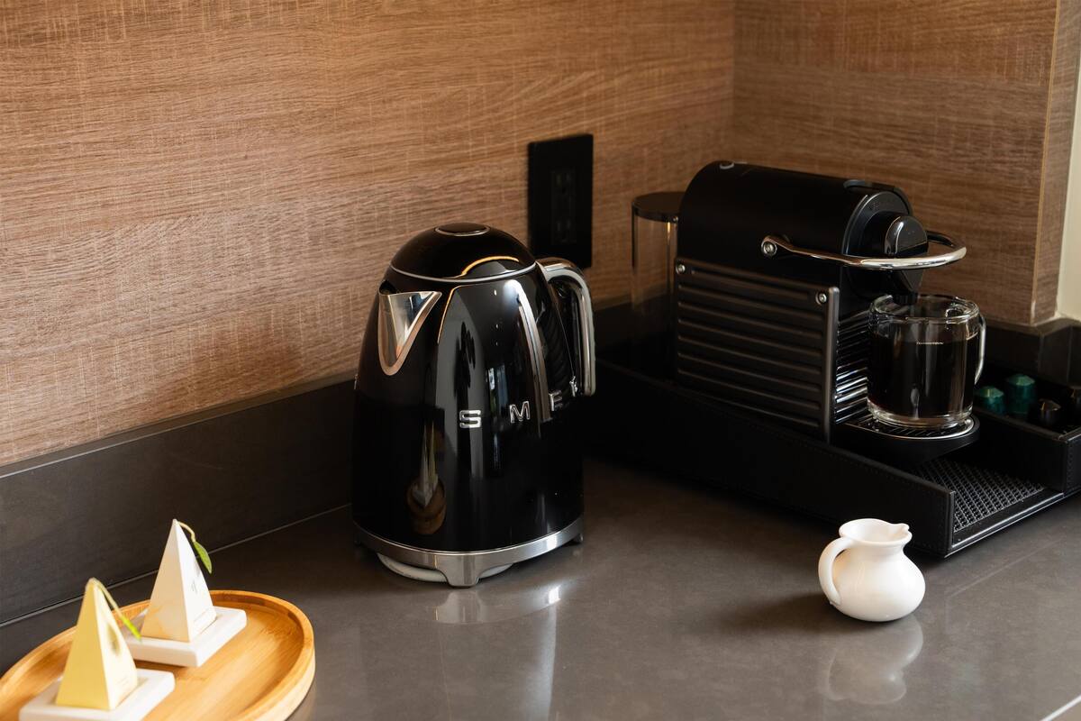 Eine Küchenzeile mit Kaffeemaschine, Wasserkocher und kleiner Krug auf einer Arbeitsplatte.
