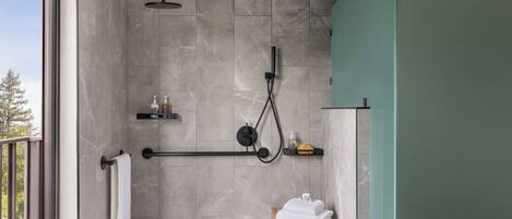 A modern shower area with a rain showerhead, a handheld showerhead, and a handheld massager. There is a wooden stool with towels and a soap dispenser on a shelf.