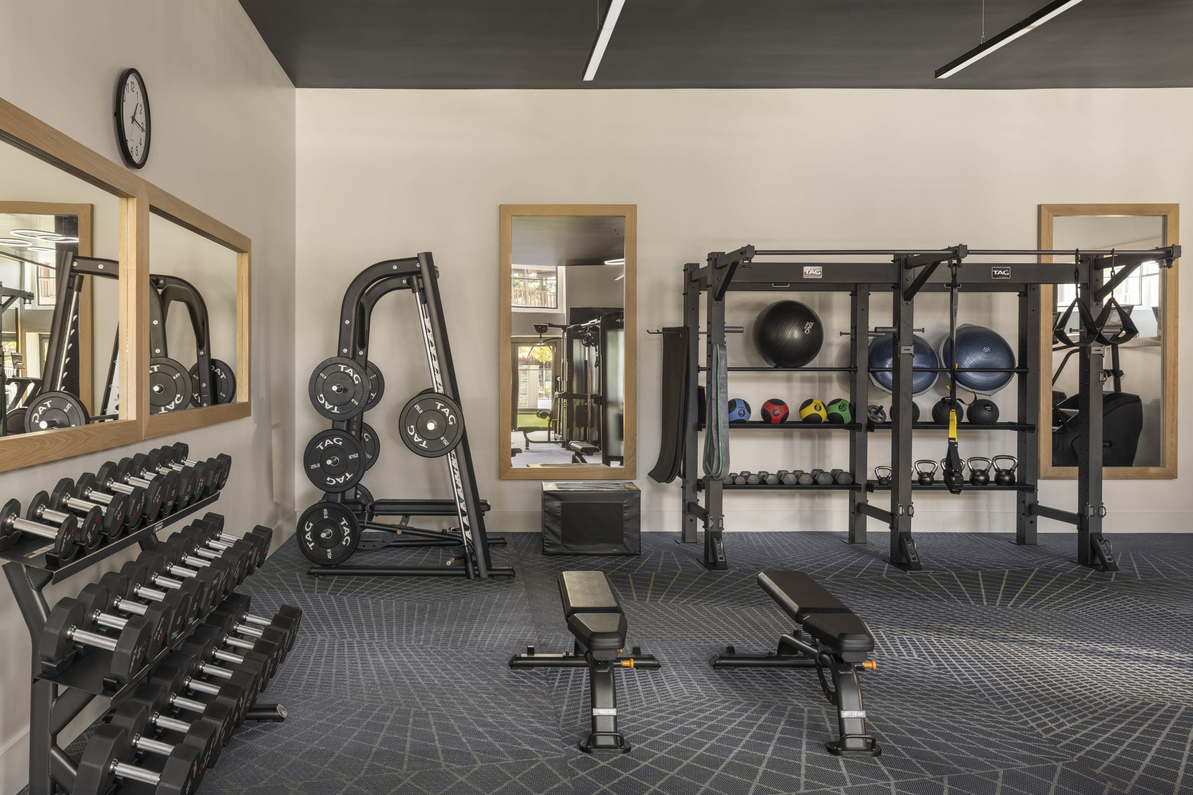 Een sportschool met gewichthefapparatuur, trainingsballen en een bank.