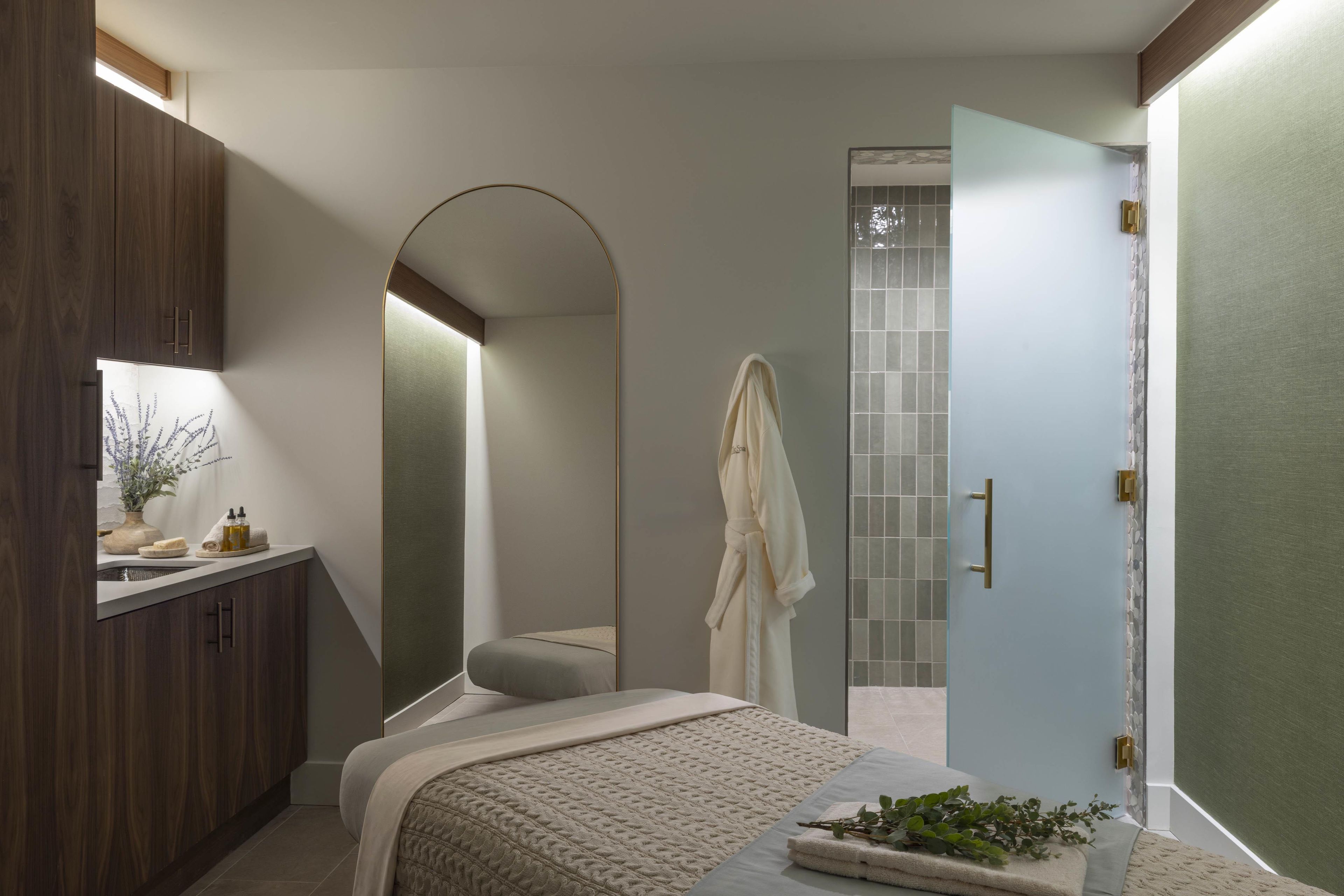 A modern bathroom with a bathtub, a large mirror, and a vanity with toiletries.