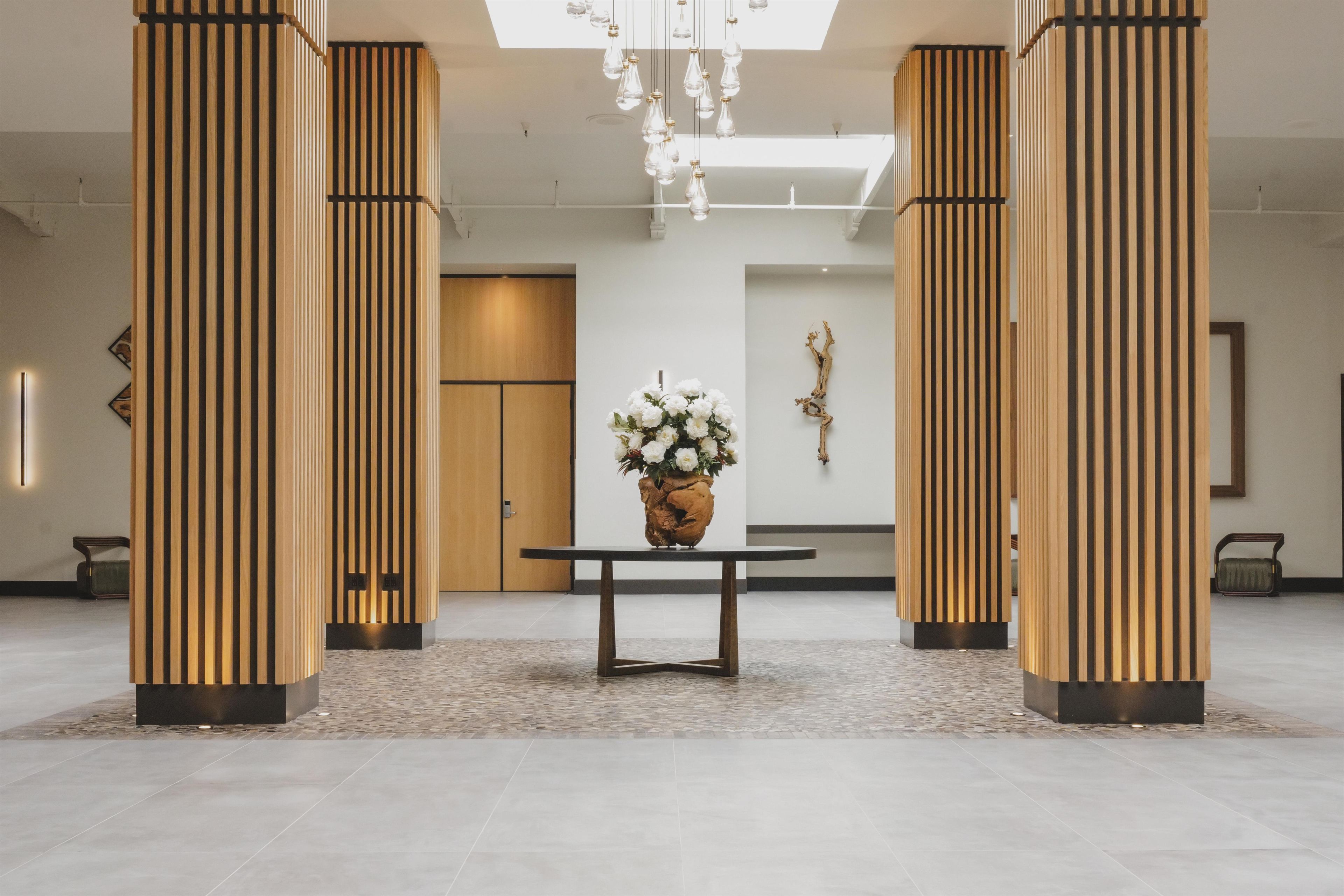 A lobby with a reception desk, a vase of flowers, and wooden columns.
