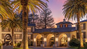 A building with a courtyard, palm trees, and a sculpture.