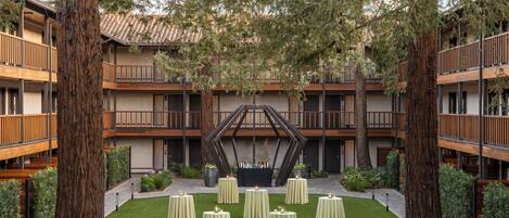 A courtyard with a central seating area, surrounded by a building with multiple balconies and a tiled roof.