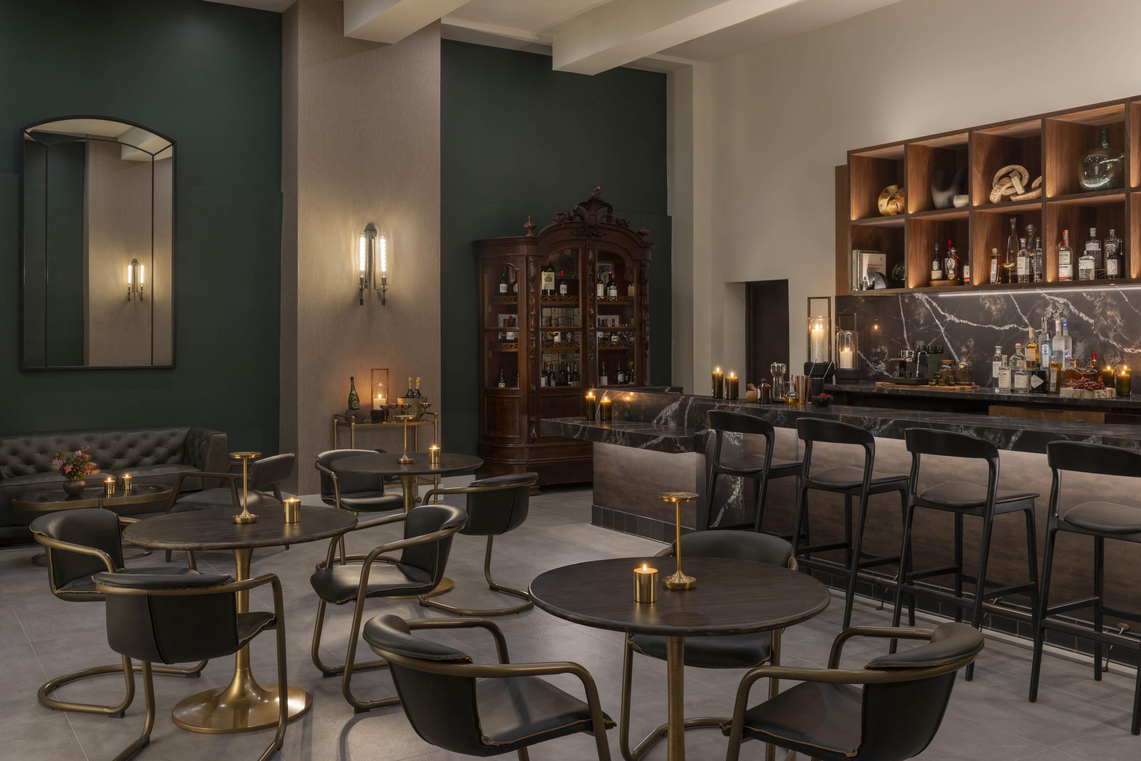 A bar area with seating and a bar counter, a large cabinet with bottles, and a mirror on the wall.