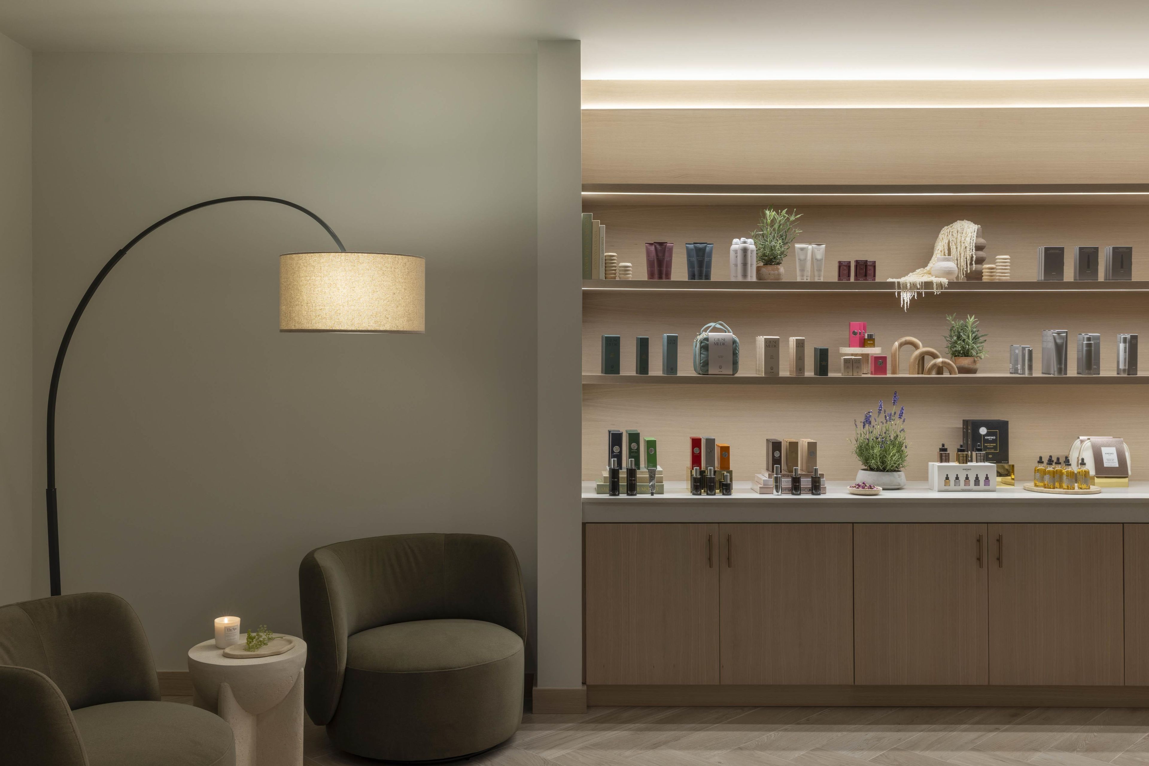Ein modernes Interieur mit einem gebogenen Sofa, einer Stehlampe und einem Regal mit verschiedenen Produkten.