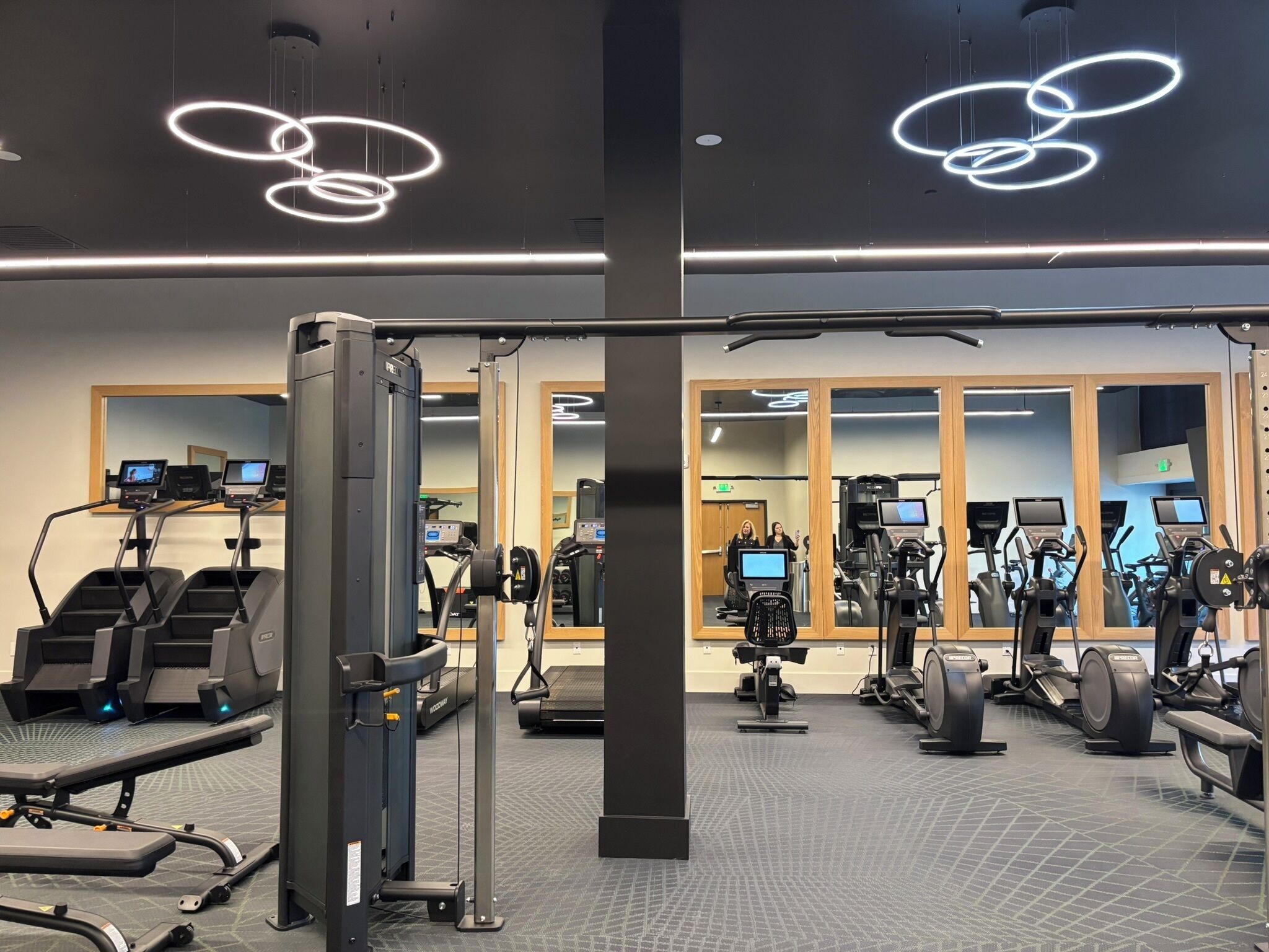 A modern gym with treadmills, elliptical machines, and weight equipment.