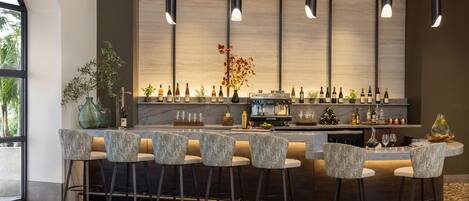 A modern bar area with a marble countertop, bar stools, and a wine rack.